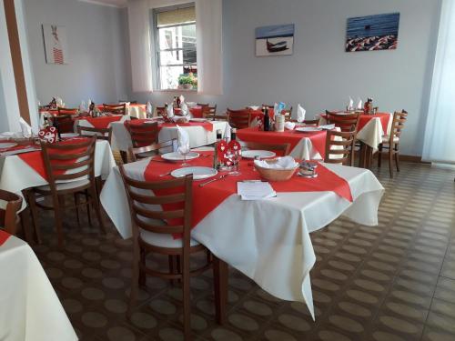 リミニにあるHotel Loraの赤と白のテーブルと椅子が備わるレストラン