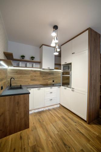 a kitchen with white cabinets and a wooden floor at Apartament Gdańska in Bydgoszcz