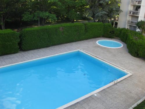 une piscine bleue avec un frisbee à côté d'une haie dans l'établissement Chambre d'hôtes dans Résidence, à Dijon