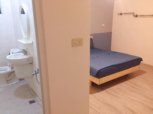 - une petite salle de bains avec un lit et un lavabo dans l'établissement Juan Guesthouse, à Pingtung