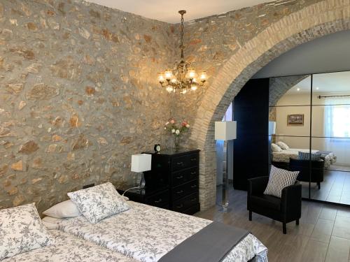 1 dormitorio con pared de piedra, cama y silla en Casa de piedra adaptada en LEscala en L'Escala