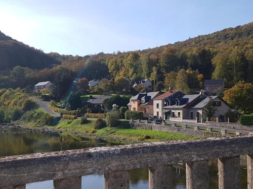 a bridge over a river with houses and a town at Gîte le Haut Rivage in Tournavaux