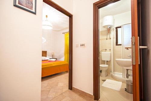 a bathroom with a sink and a toilet and a bed at Apartments Petrčane Welcome in Petrcane