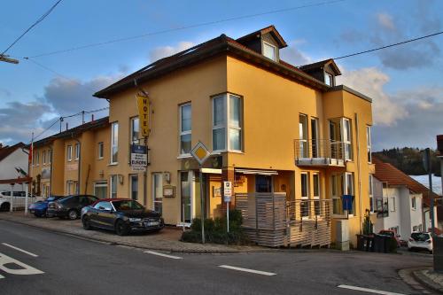 a yellow building with cars parked in front of it at Hotel-Bistro-Europa in Merchweiler