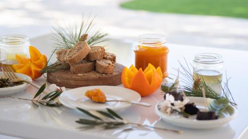 Una mesa cubierta con platos de comida y tarros de miel. en Nature Suites Puig Campana by AR Hotels & Resorts, en Finestrat