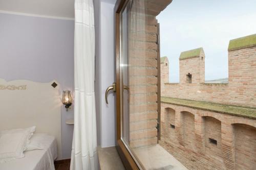 ein Schlafzimmer mit einem Fenster mit Ziegelwand in der Unterkunft Dimora della Rovere in Gradara