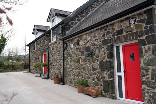 a brick building with a red door and a sidewalk at The Barn at BallyCairn in Larne