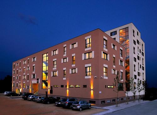 een groot gebouw met auto's geparkeerd op een parkeerplaats bij Melrose Apartments in Bratislava