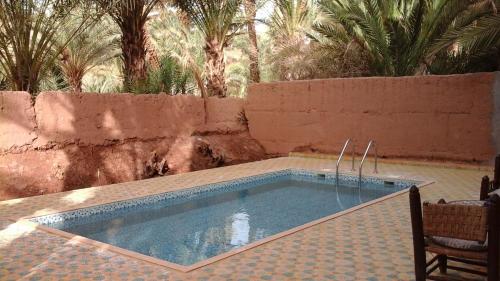 a swimming pool in a yard with palm trees at Dar Nakhla - Zagora guest house in Zagora