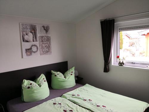 ein Schlafzimmer mit einem Bett mit grünen Kissen und einem Fenster in der Unterkunft Ferienhaus MaLeFi 1 am Gülser Moselbogen in Koblenz