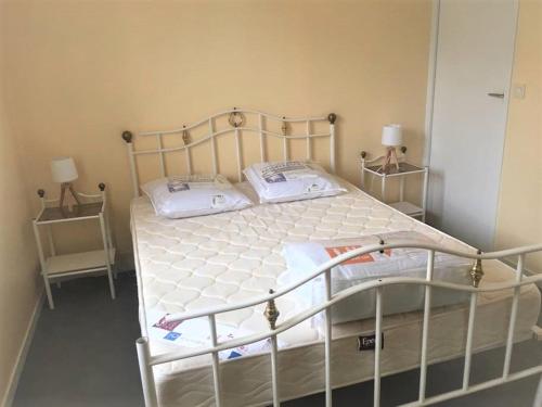 un lit avec deux oreillers dessus dans une chambre dans l'établissement Cabourg centre, appartement pour 4 personnes à 100m de la mer, à Cabourg