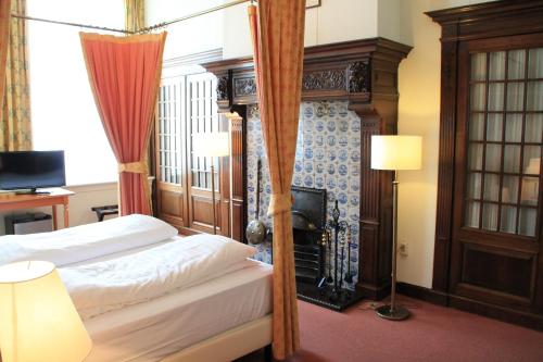 a bedroom with a canopy bed and a fireplace at De Doelen in Leiden