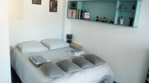 - une chambre avec un lit avec deux oreillers et une étagère dans l'établissement Résidence Mayol - Draps et serviettes fournis, à Toulon