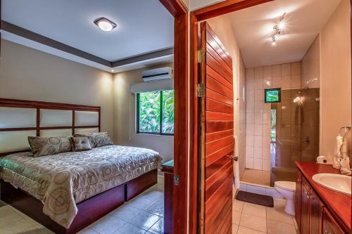 a bedroom with a bed and a shower and a sink at Hidden Palms in Nosara