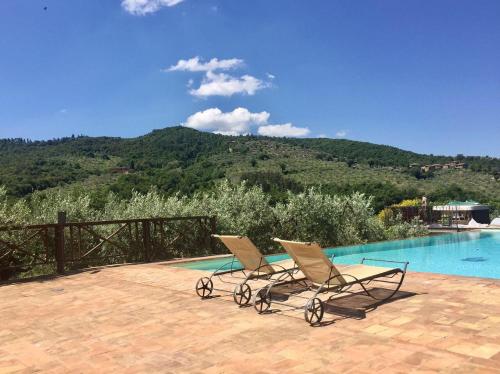 two lounge chairs sitting next to a swimming pool at Fontanaro Farm and Culinary School in Paciano
