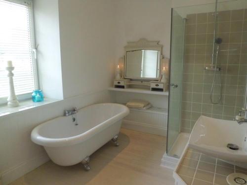 a bathroom with a tub and a sink and a mirror at The Chantry in Callington