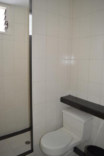 a bathroom with a toilet and a white tiled wall at Hotel Tiburon in Caracas