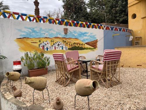 a patio with chairs and a table and a mural at The Mango Guest House in Aswan