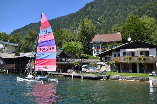 a sail boat in the water next to a house at Villa Marienhof in Annenheim