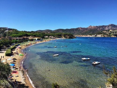 a beach with people and boats in the water at appartamento l'angolo in Capoliveri