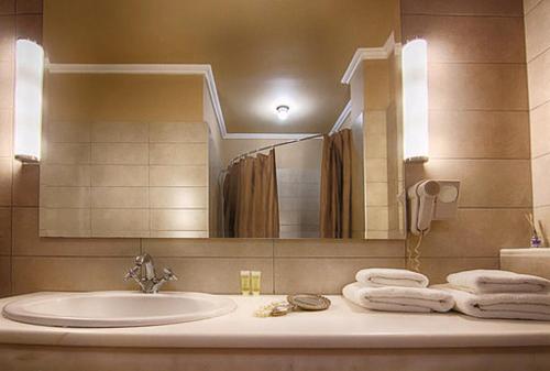 a bathroom with a sink and a mirror and towels at Galaxy Hotel in Athens