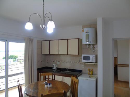 a kitchen with a table and a sink and a microwave at Urunday Apart Hotel in Posadas