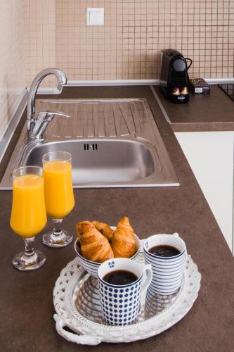 a sink with two glasses of orange juice and croissants at Kassandra Studios in Polychrono