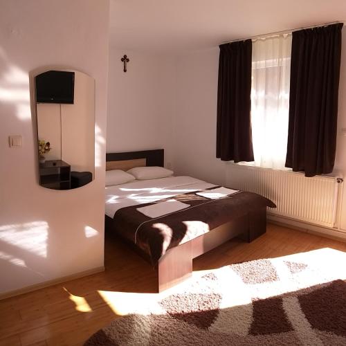 a bedroom with a bed and a mirror and a window at Pensiunea Denis in Cârțișoara