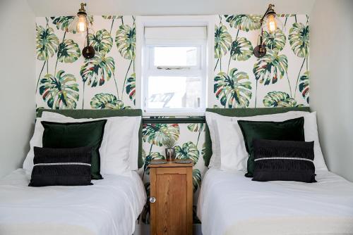 two beds in a room with palm trees on the wall at The Cottage and The Nook in Gretton