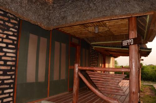 a porch of a hut with a sign on it at Irungu Forest Safari Lodge in Katunguru