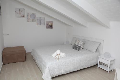 ein weißes Schlafzimmer mit einem Bett mit einer Schleife darauf in der Unterkunft Rosy House - Hospitality in Pimonte