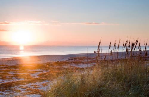 a beach with the sun setting on the ocean at Port d'Hiver Bed and Breakfast in Melbourne Beach