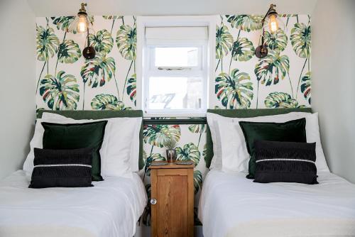 two beds in a room with palm trees on the wall at The Cottage, Gretton (Cotswolds) in Gretton