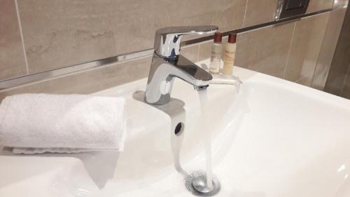 lavabo con grifo y papel higiénico en Studio Metropole Praha, en Praga