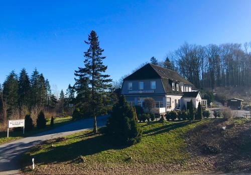 a house with a tree on the side of a road at Waldhotel "Peter aufm Berge" in Bielefeld