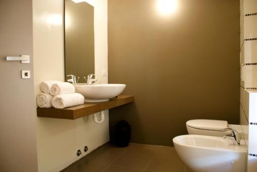 a bathroom with a sink and a toilet and a mirror at Albergo Diffuso Vulcano Village in Castro