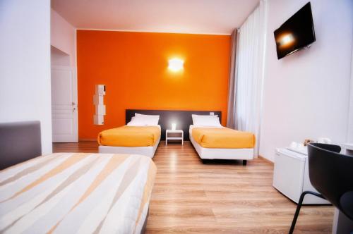 two beds in a room with an orange wall at Torino 1854 Affittacamere in Turin