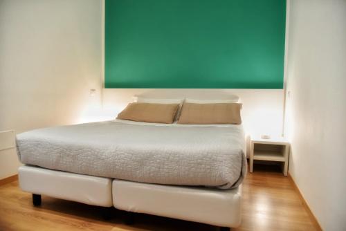 a bedroom with a white bed with a green board above it at Torino 1854 Affittacamere in Turin