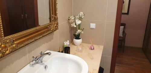 een badkamerwastafel met spiegel en een vaas met bloemen bij Casa da Quinta in Funchal