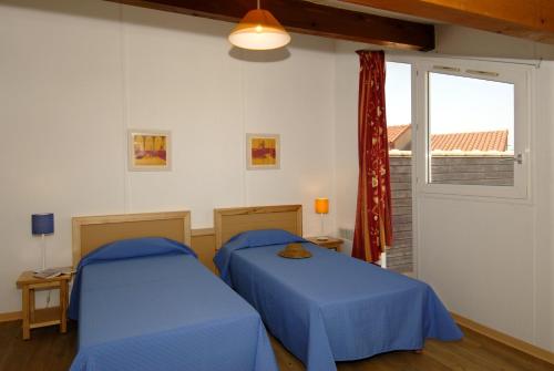 Dos camas en una habitación con ventana. en Goélia Le Village Club Marin, en Port-la-Nouvelle