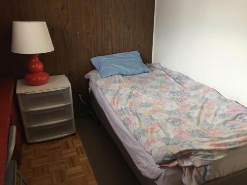 a small bedroom with a bed and a lamp on a night stand at Private Room near Airport in Mississauga