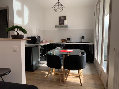 een kleine keuken met een tafel en zwarte stoelen bij The Cocooning in Tours