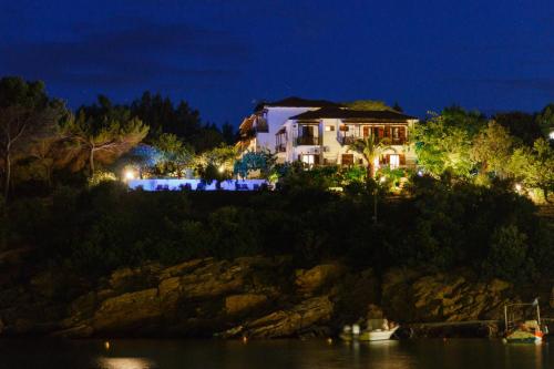 una casa en una colina al lado del agua por la noche en Studios Avra, en Agios Georgios