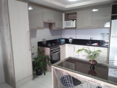 a kitchen with white cabinets and a counter top at Apto Aconchego da Serra - Bairro Maria Goretti in Bento Gonçalves