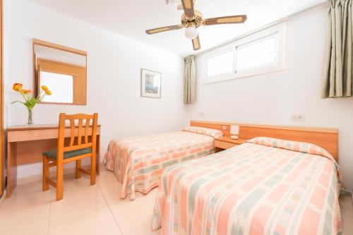 1 dormitorio con 2 camas, escritorio y silla en Apartamentos Lido, en Ibiza