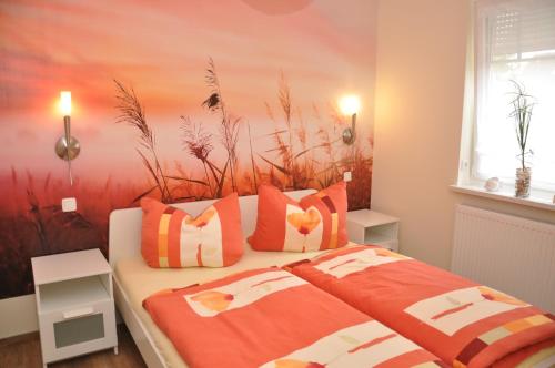 a bedroom with a bed with orange and white pillows at Ferienhaus Müritzzauber / EG-Appartement in Marienfelde