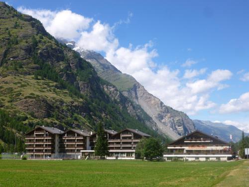 a large building with a mountain in the background at Monte Rosa D 412 in Täsch