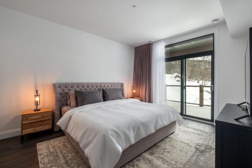 1 dormitorio con cama grande y ventana grande en Horizon 104 by Tremblant Prestige, en Mont-Tremblant