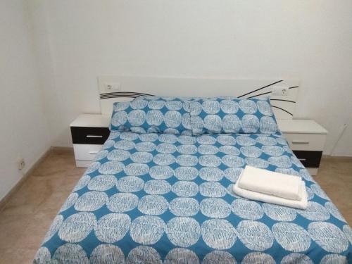 a bed with a blue and white comforter in a room at Piso Almería playa in Almería