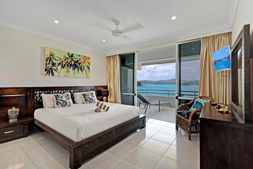 a bedroom with a bed and a view of the ocean at Frangipani Apartments on Hamilton Island by HIHA in Hamilton Island